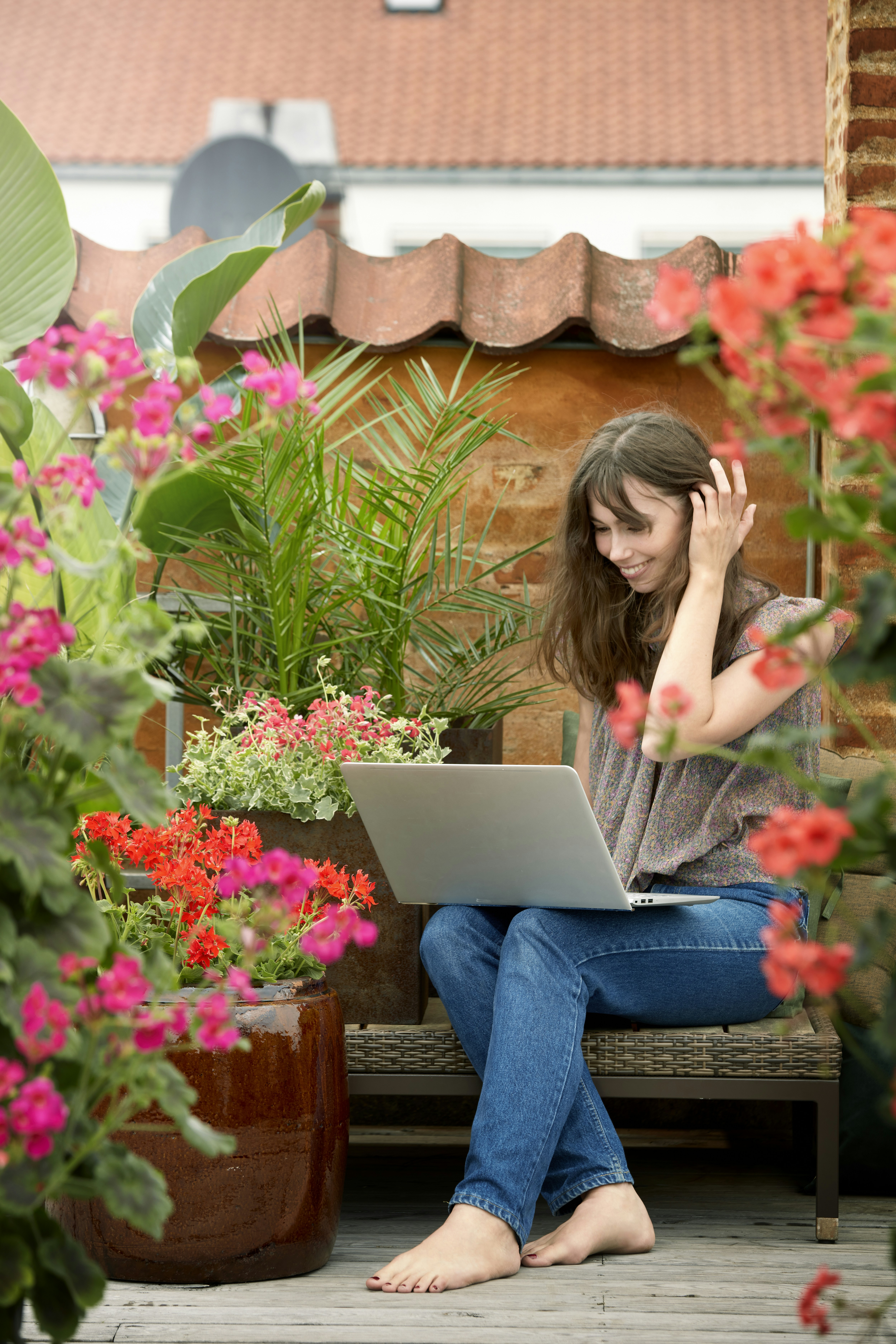 woman in blue denim jeans sitting on brown wooden bench using macbook
