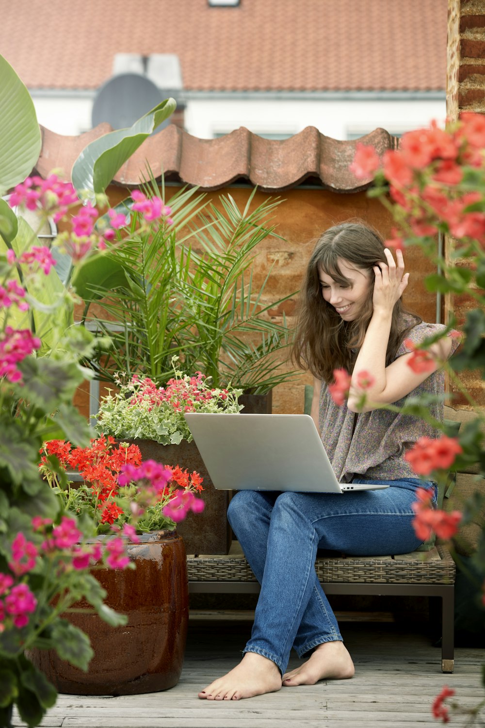 woman in blue denim jeans sitting on brown wooden bench using macbook