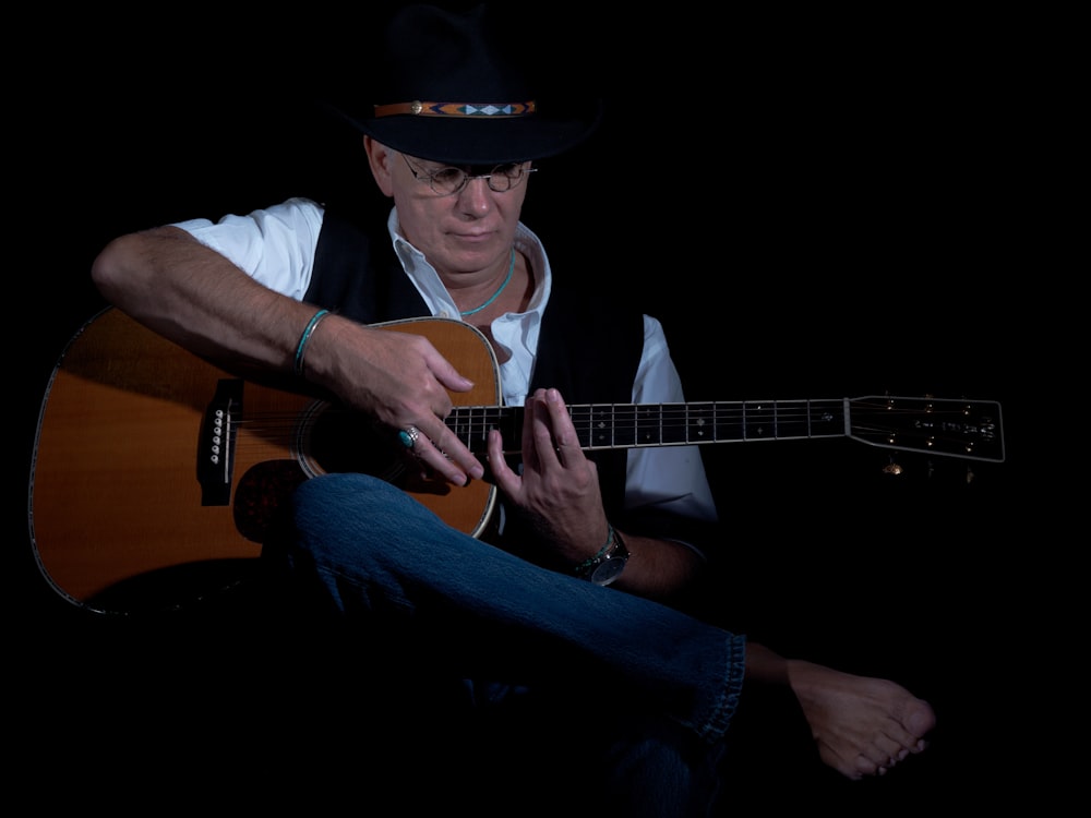 man in white button up shirt playing acoustic guitar