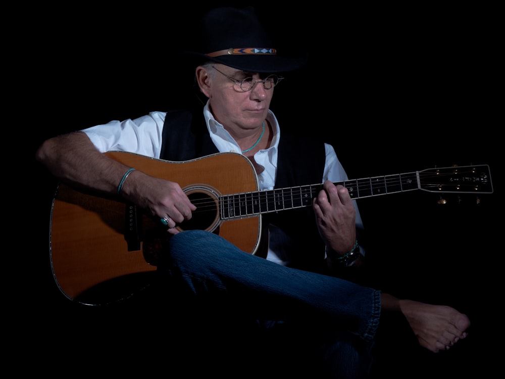 man in black hat playing guitar