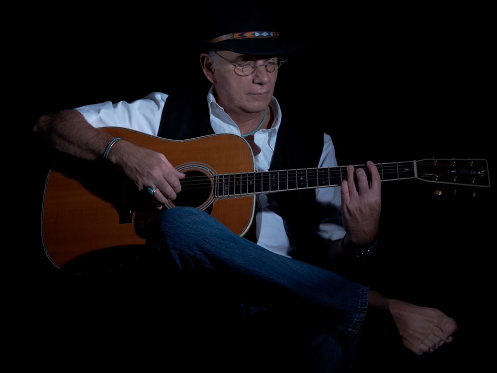 man in black hat playing guitar