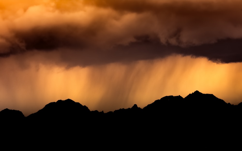 silhouette of mountain under cloudy sky during daytime