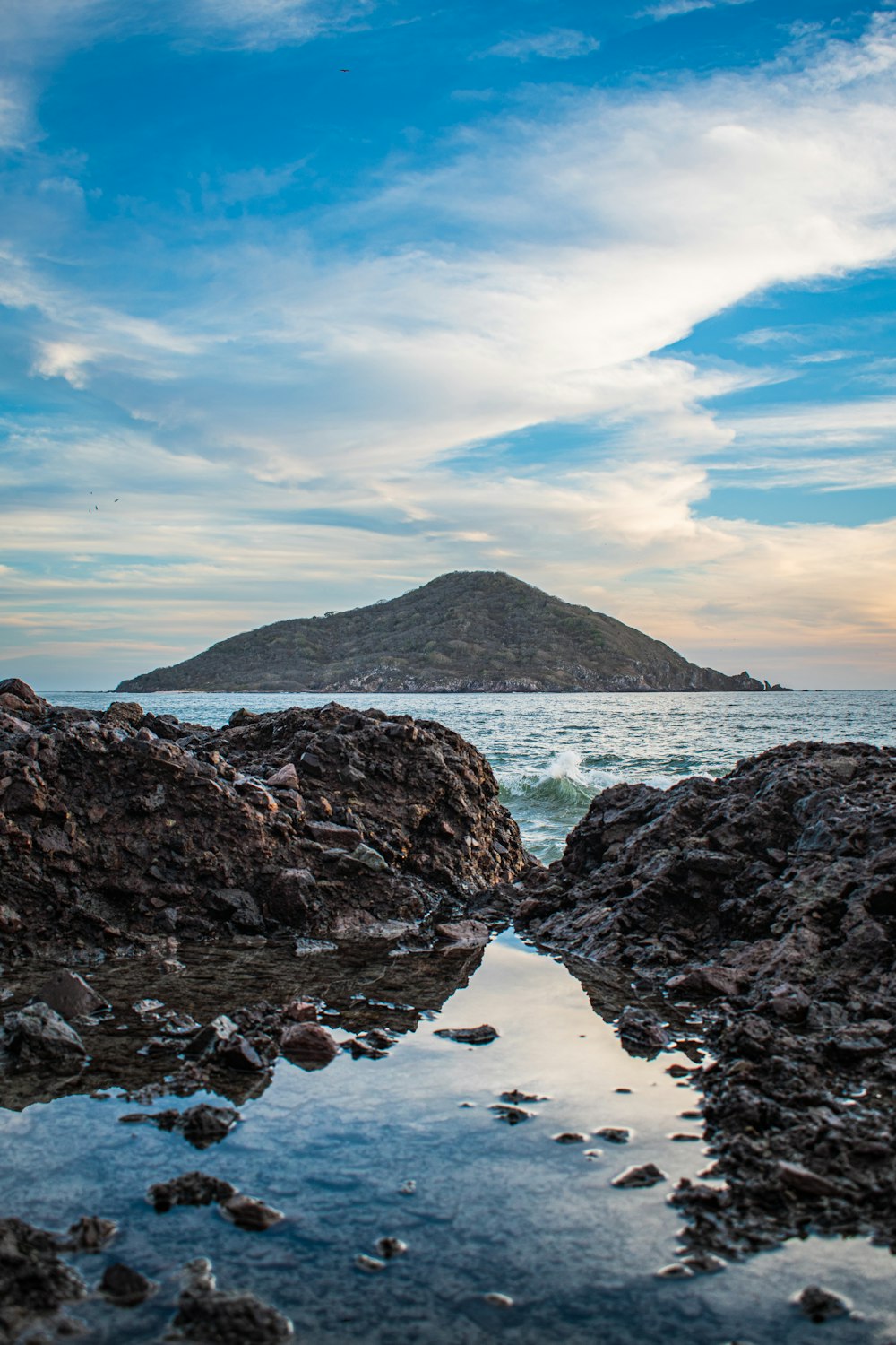 black rock formation on sea shore during daytime