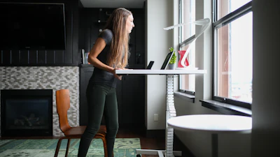 woman in gray tank top and black denim jeans standing beside white wooden shelf