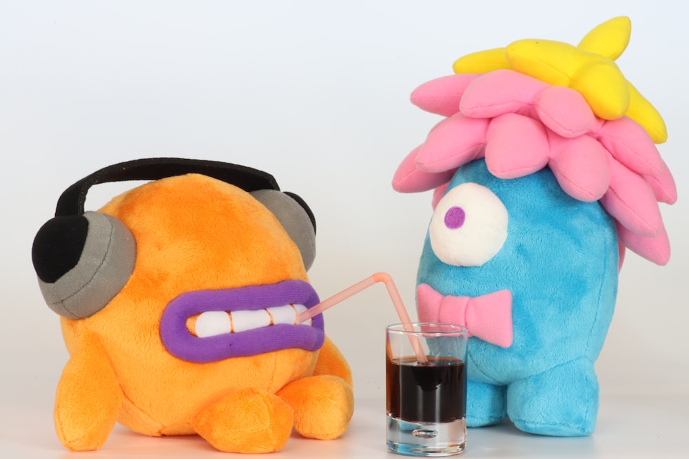 blue and pink plush toy beside clear drinking glass