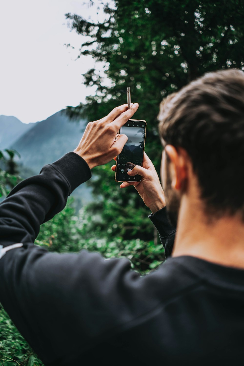 man in black long sleeve shirt holding black smartphone