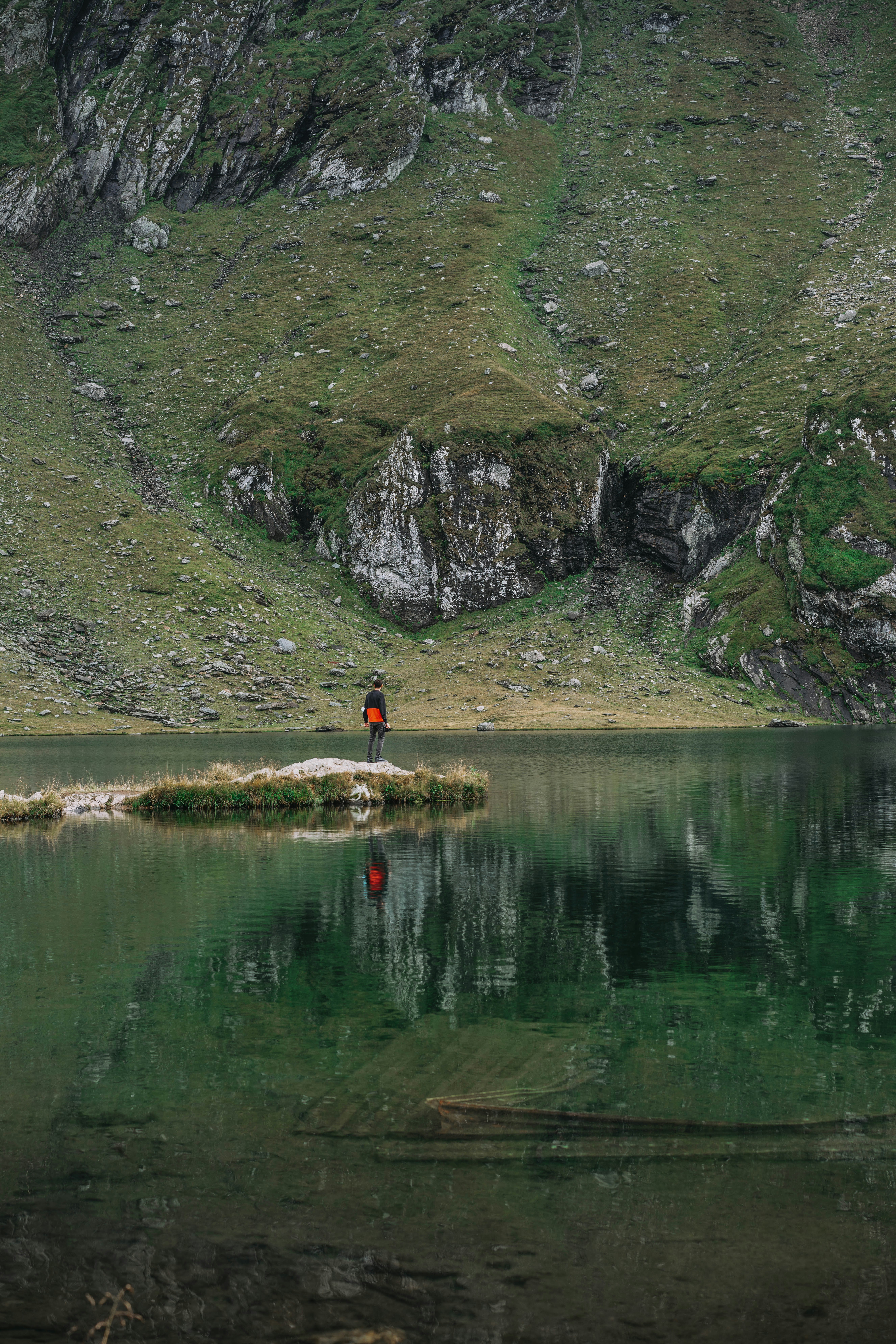 person in red shirt standing near lake during daytime