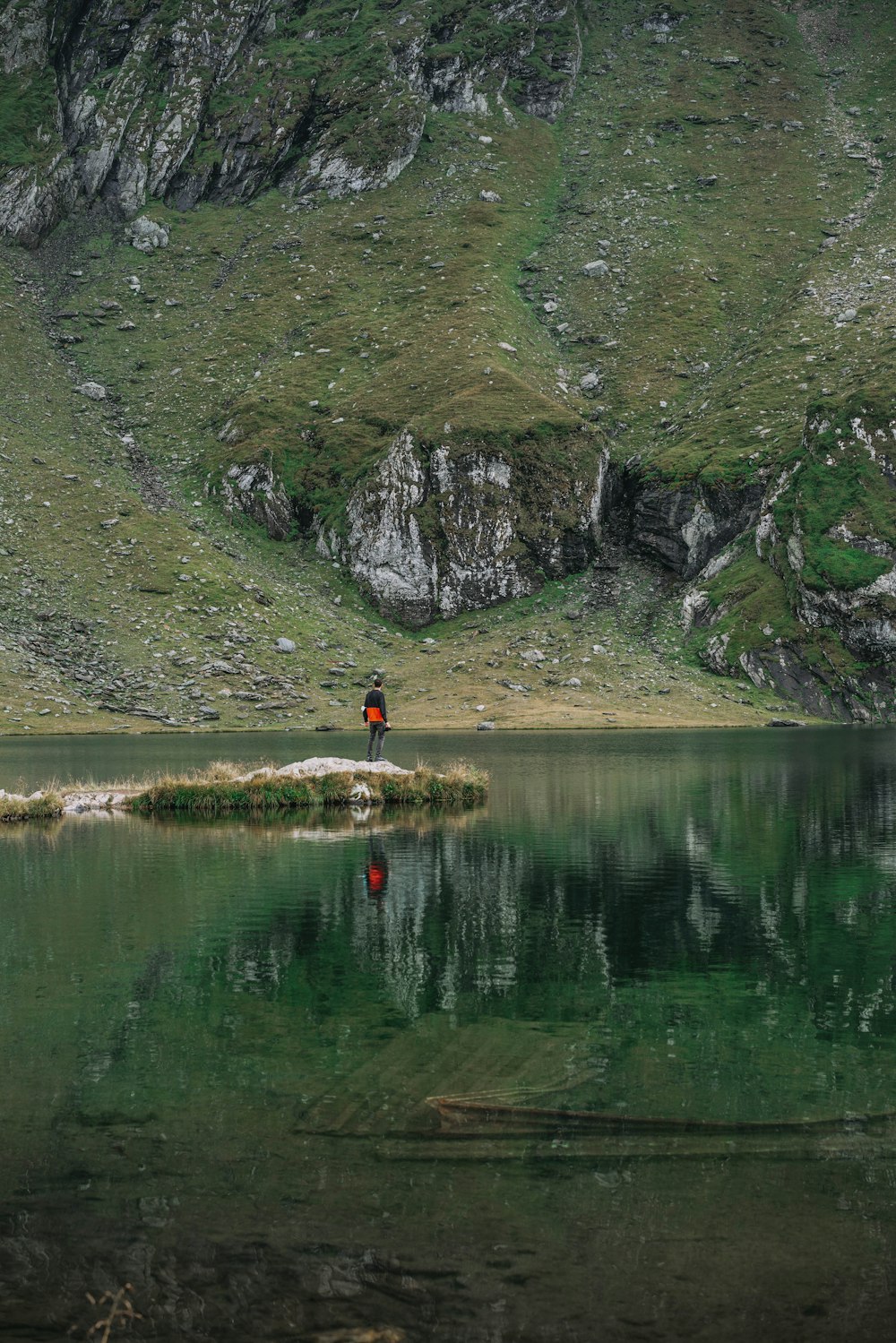 Person im roten Hemd, die tagsüber in der Nähe des Sees steht