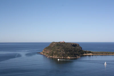 person standing on brown rock formation in front of blue sea during daytime