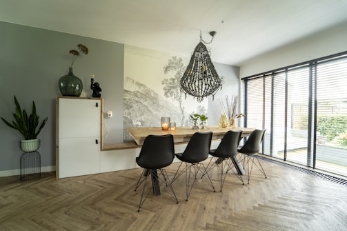A dining area with a polished wooden table, black chairs, and soft cream walls accented by subtle gold lighting.