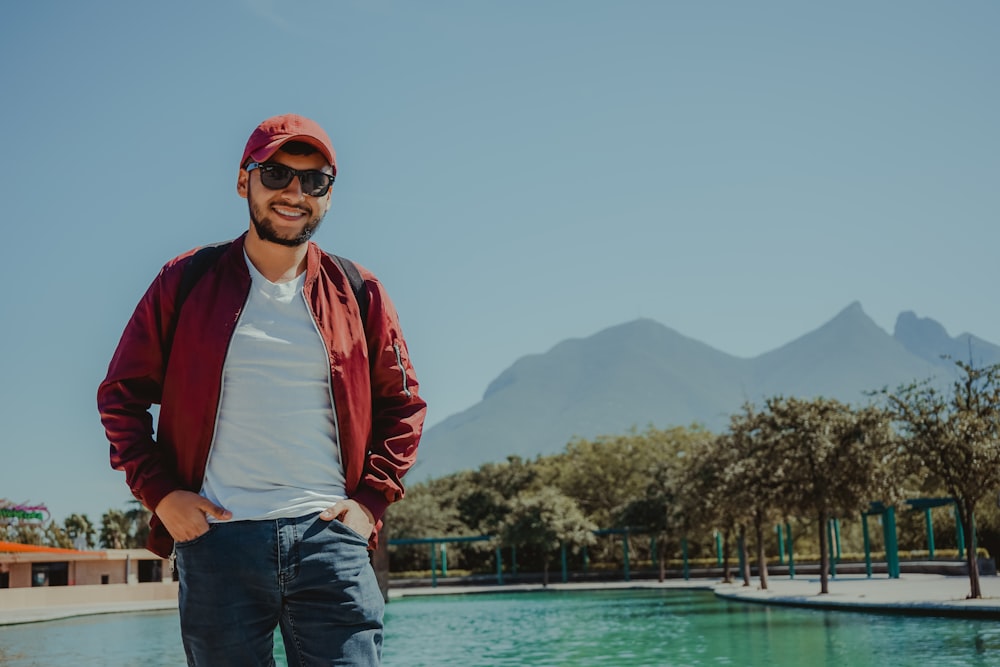 man in red jacket standing near body of water during daytime