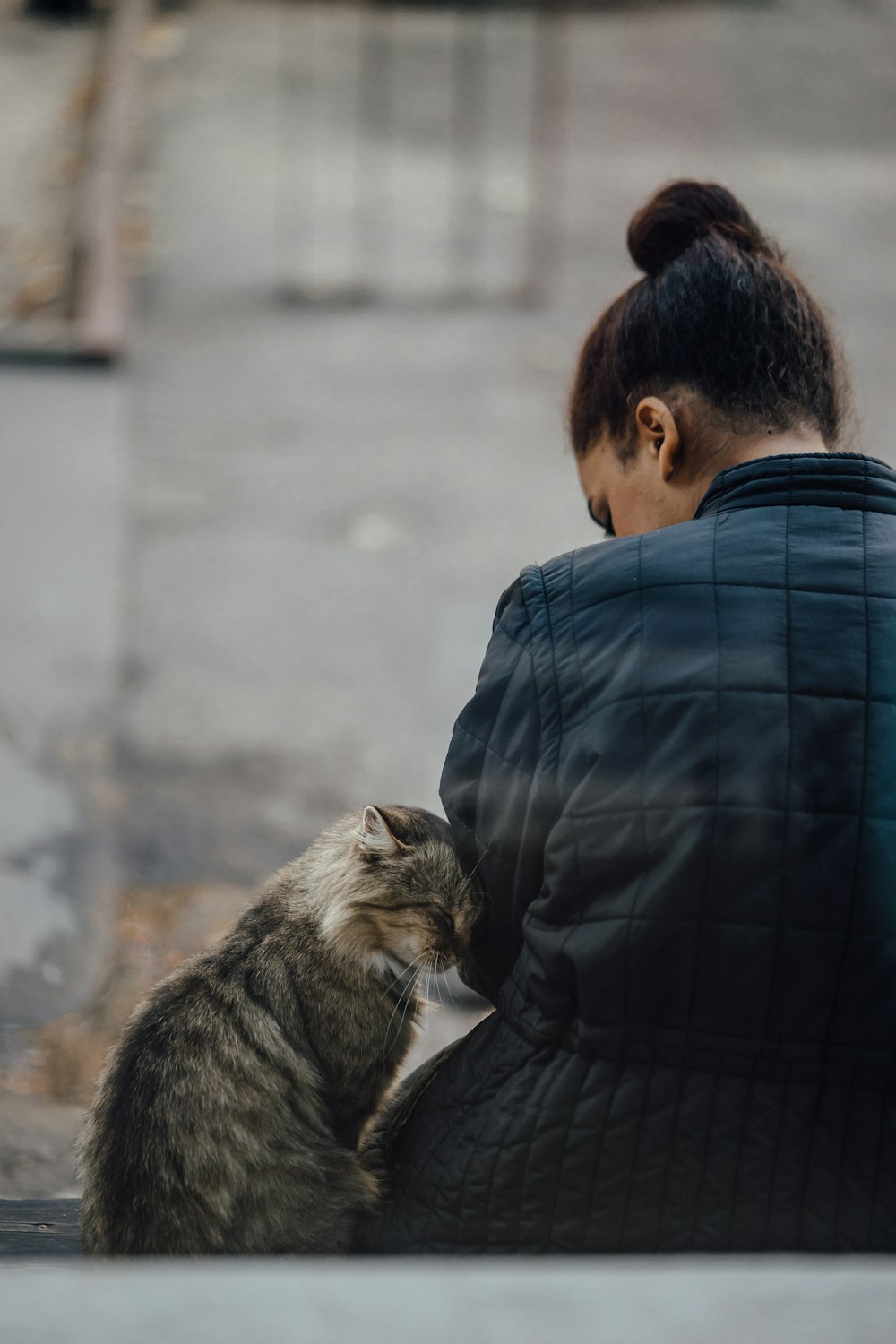 man in black leather jacket carrying brown tabby cat