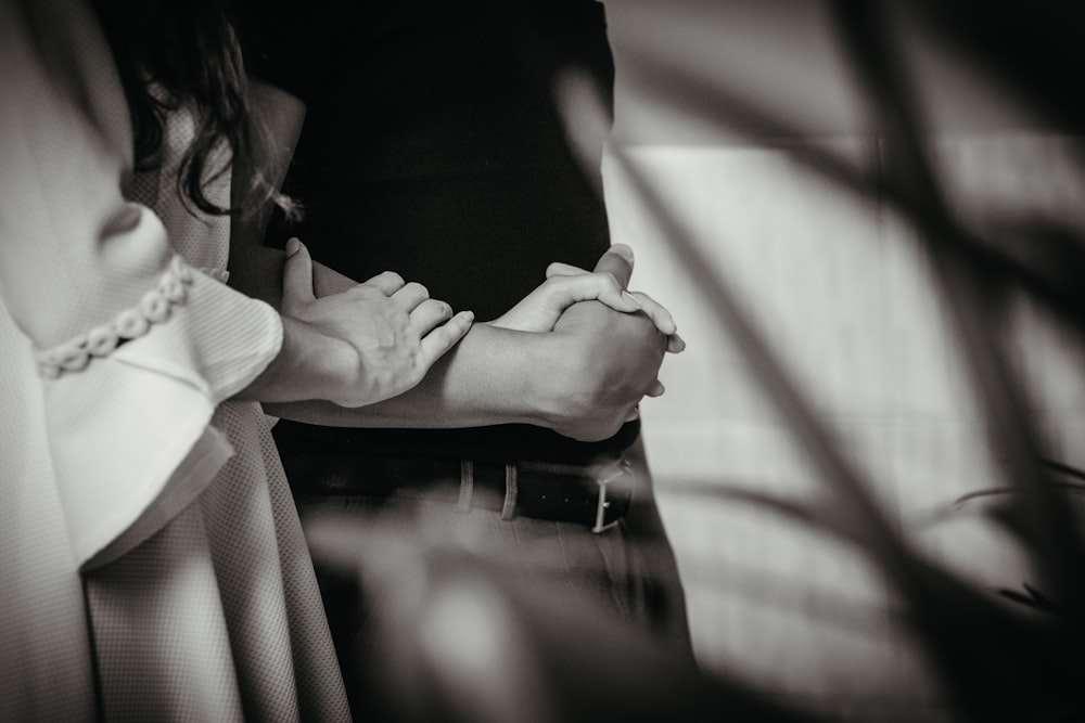 Foto en escala de grises de mujer con camisa blanca de manga larga sosteniendo la mano del hombre