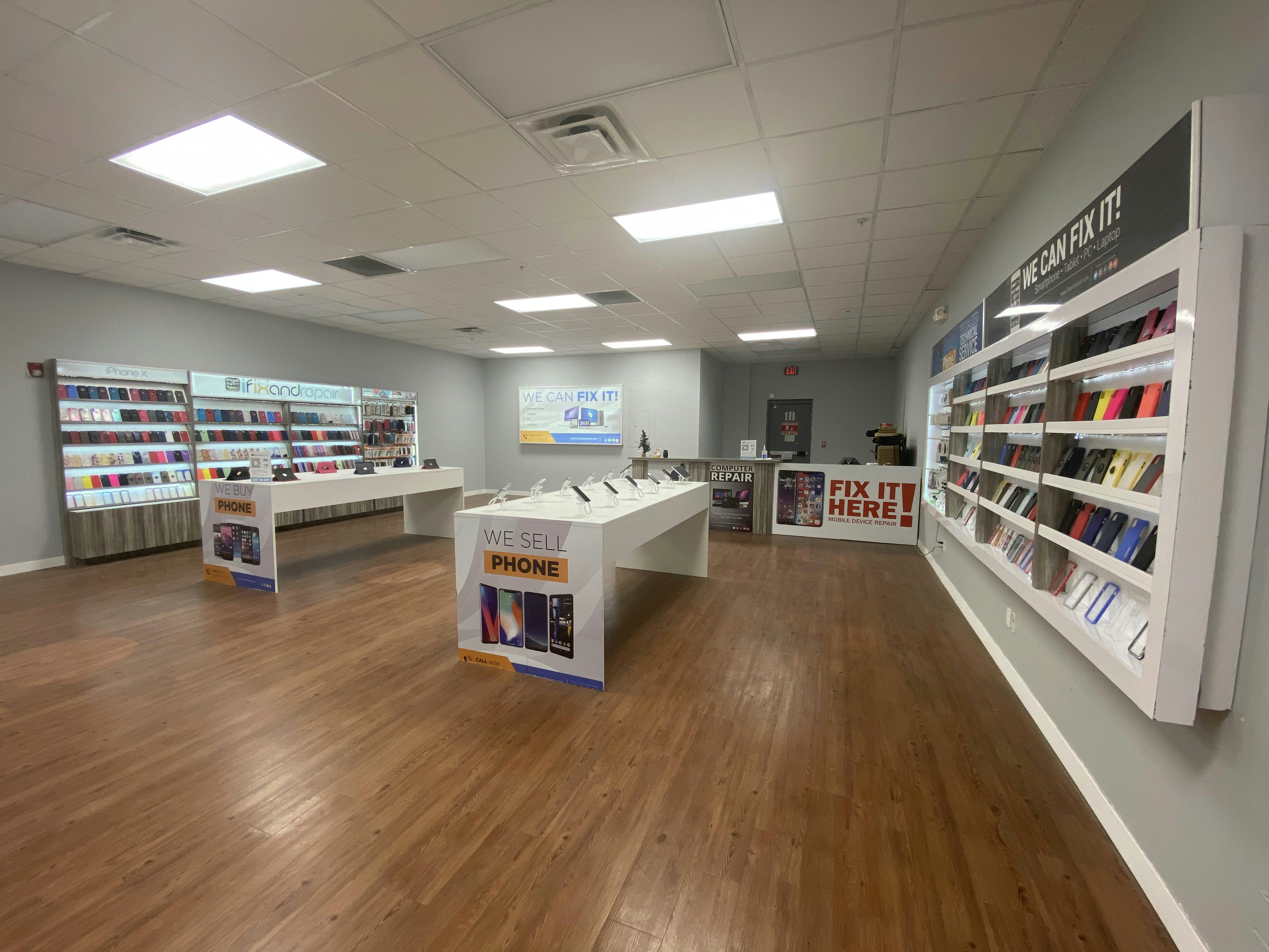 Clean phone repair shop counter with organized tools, spare parts bins, and professional signage under bright lighting