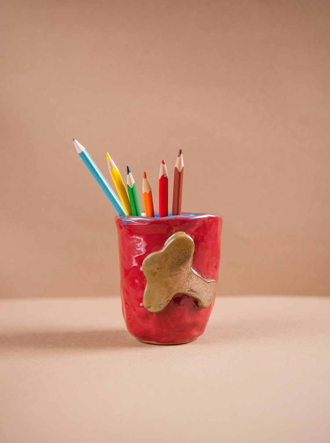 red and green ceramic mug with pencils