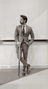 man in brown suit holding walking stick
