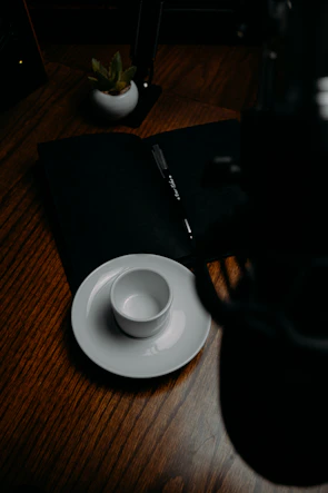 A peaceful morning scene with a cup of herbal tea and a notebook beside a small potted plant.