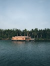 A serene houseboat floating on Dal Lake surrounded by lush greenery and mountains.