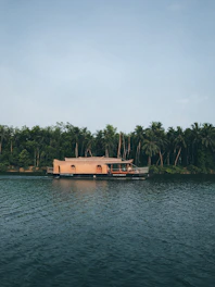 A cozy houseboat floating peacefully on Dal Lake with Himalayan peaks in the background at sunset.