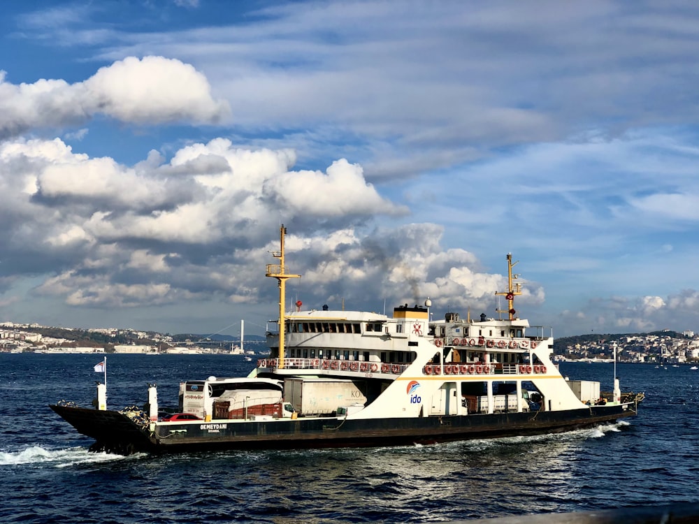 weißes und braunes Schiff auf See unter weißen Wolken und blauem Himmel tagsüber