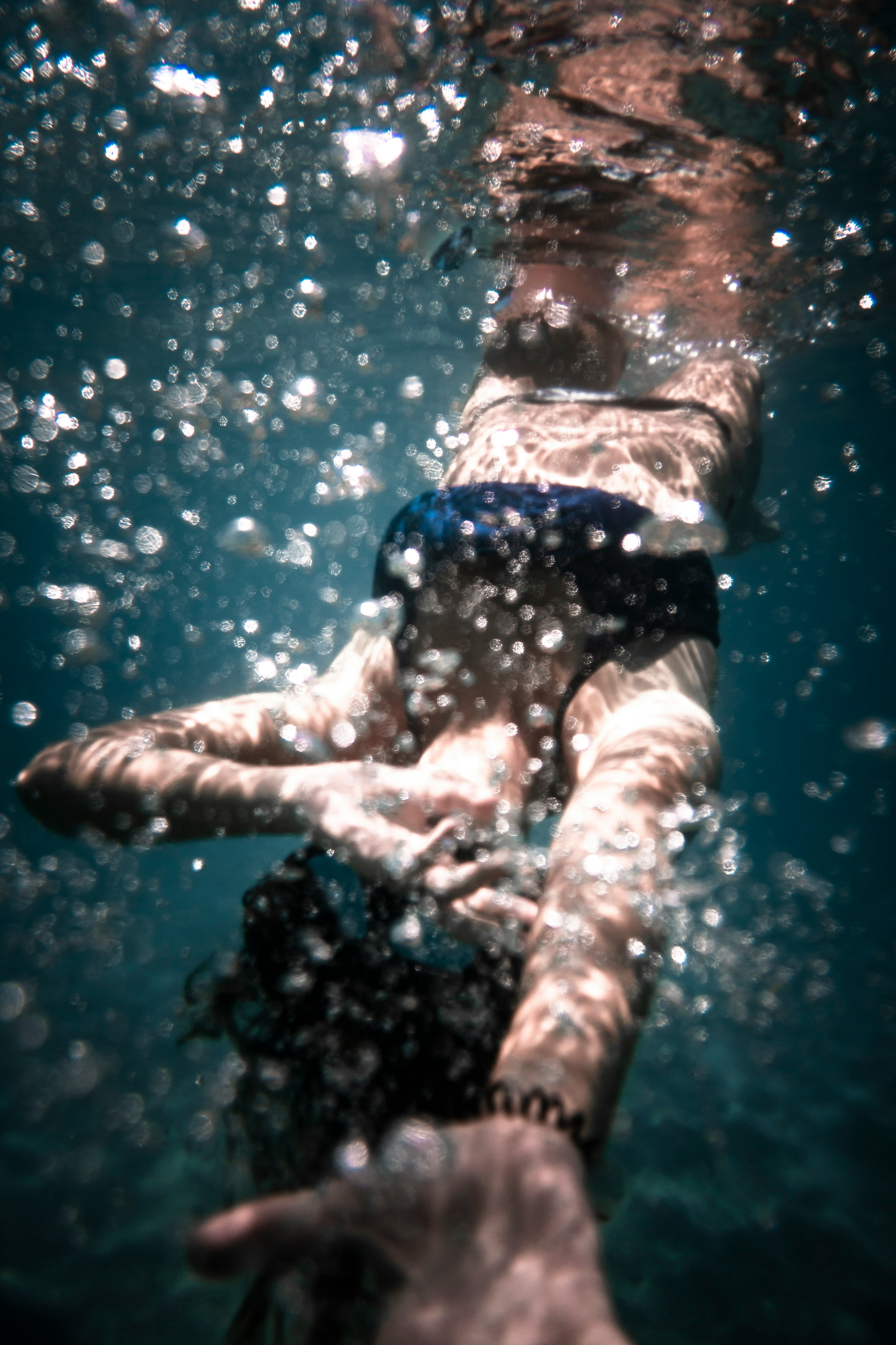 person in blue and white floral shorts in water