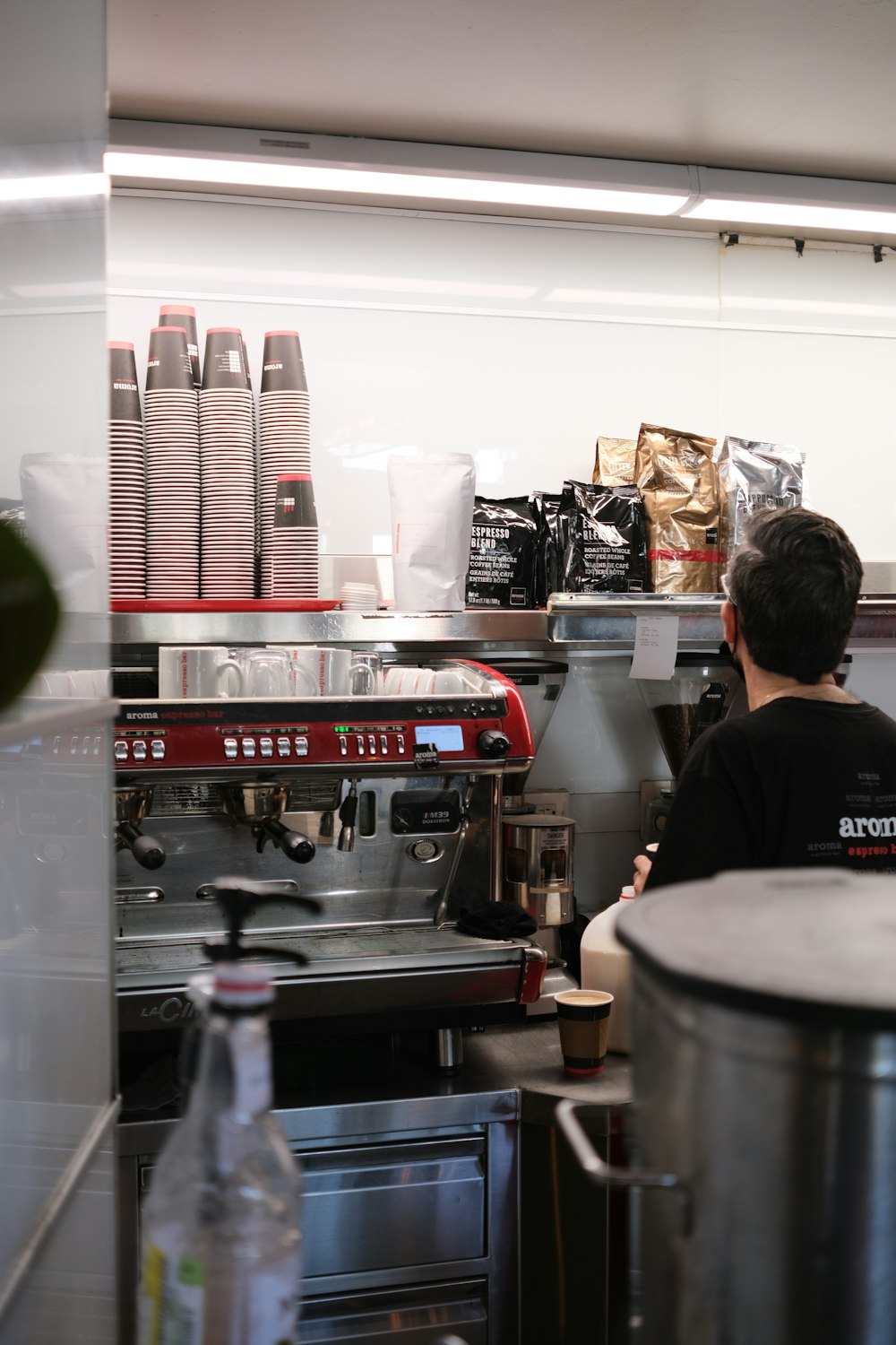 man in black jacket standing in front of gray and red coffee maker