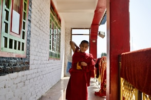 woman in red and yellow dress standing beside red wooden door