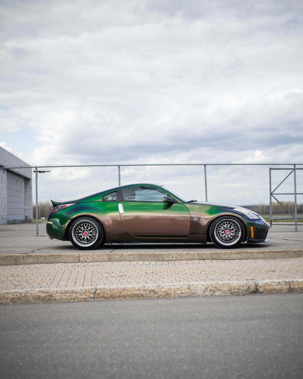 green coupe parked beside white building