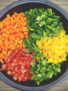 A vibrant mix of colorful vegetable powders in small bowls with fresh tomatoes, carrots, and herbs around them.