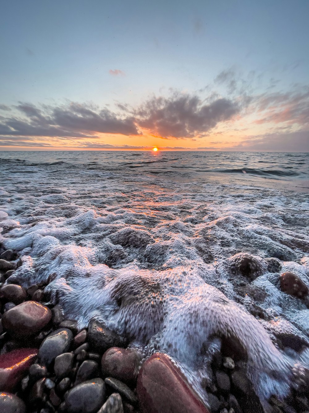 Rivage rocheux sous un ciel nuageux au coucher du soleil