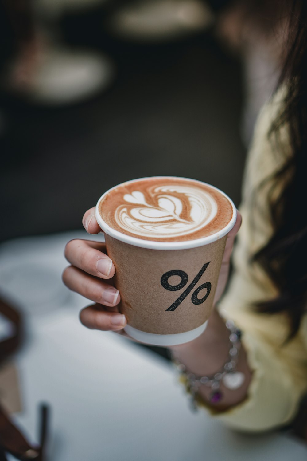 Person mit weißer und brauner Kaffeetasse