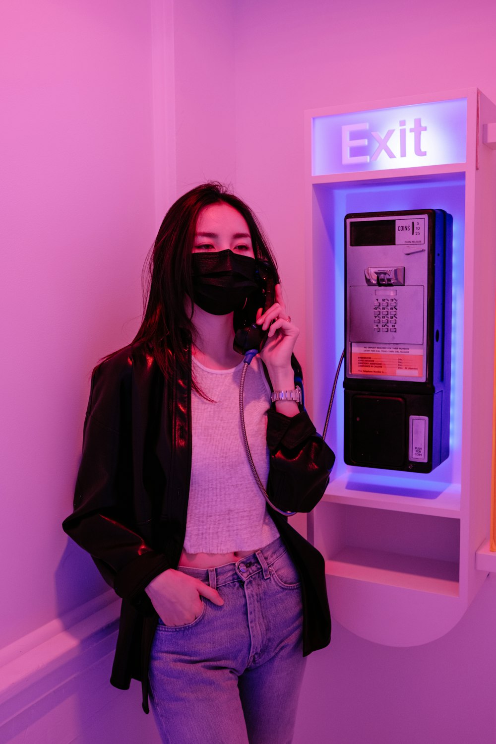 woman in black leather jacket standing near white wall