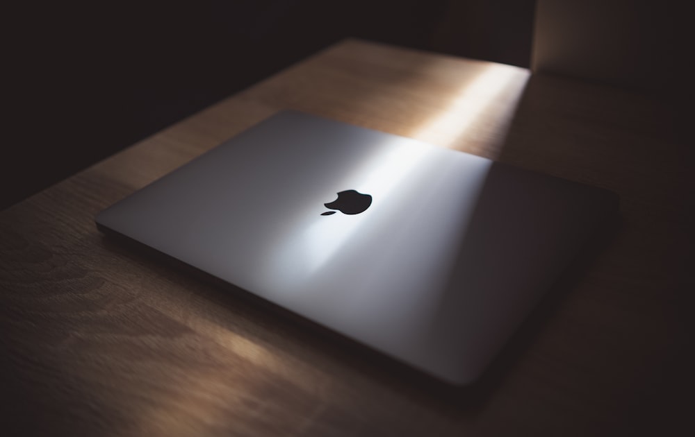 茶色の木製テーブルの上にシルバーのMacBook