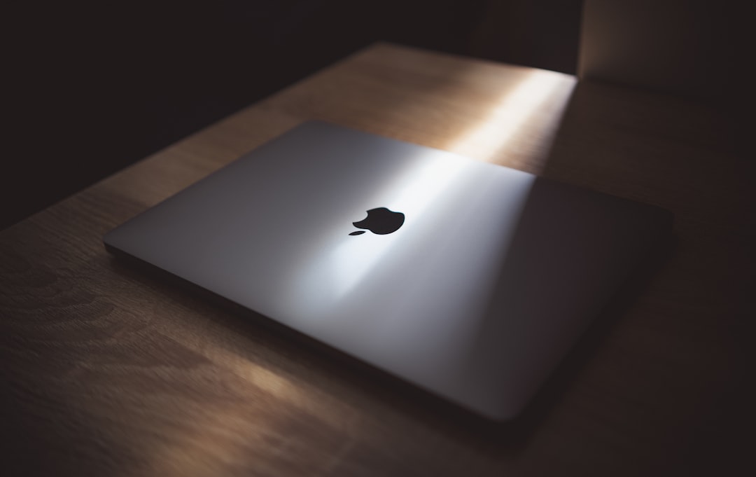 silver macbook on brown wooden table