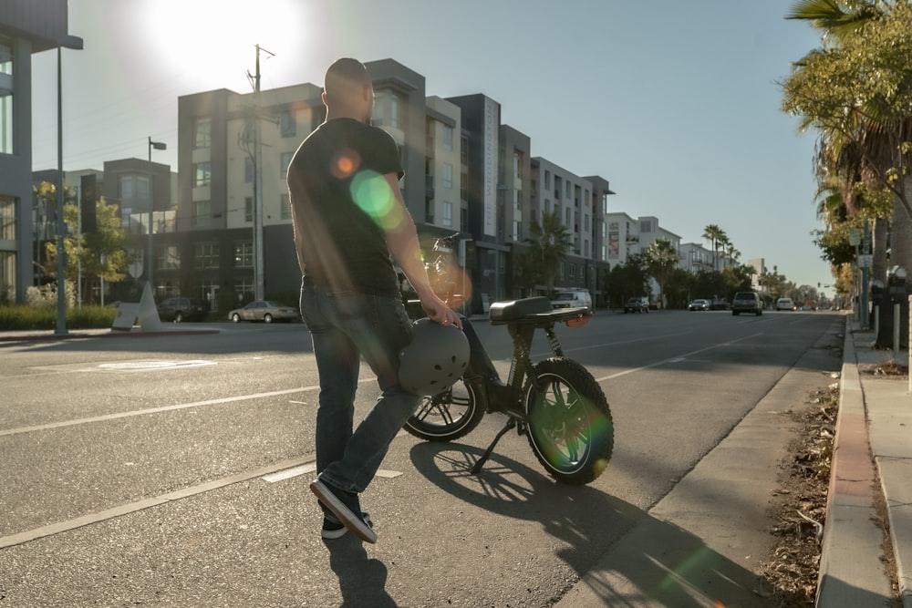 man in black jacket and black pants riding on black bicycle during daytime