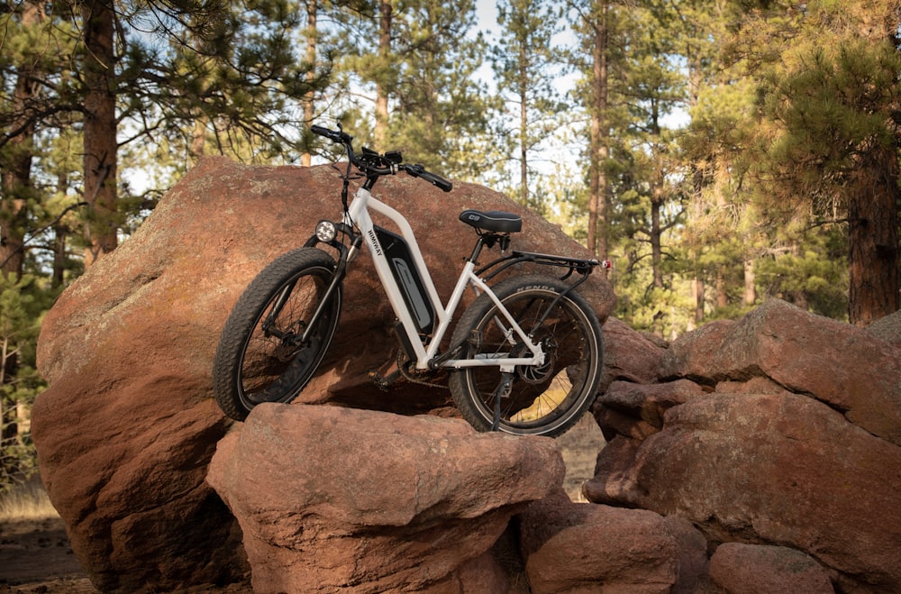 a bicycle is parked on a rock in the woods