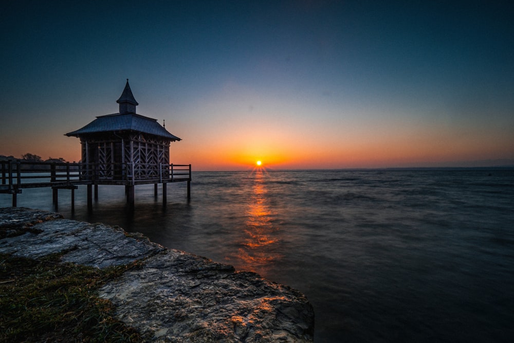 silhouette of gazebo on sea shore during sunset