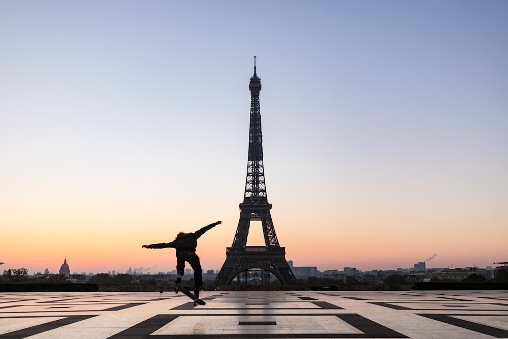 silhouette of man jumping on gray concrete pathway near eiffel tower during sunset