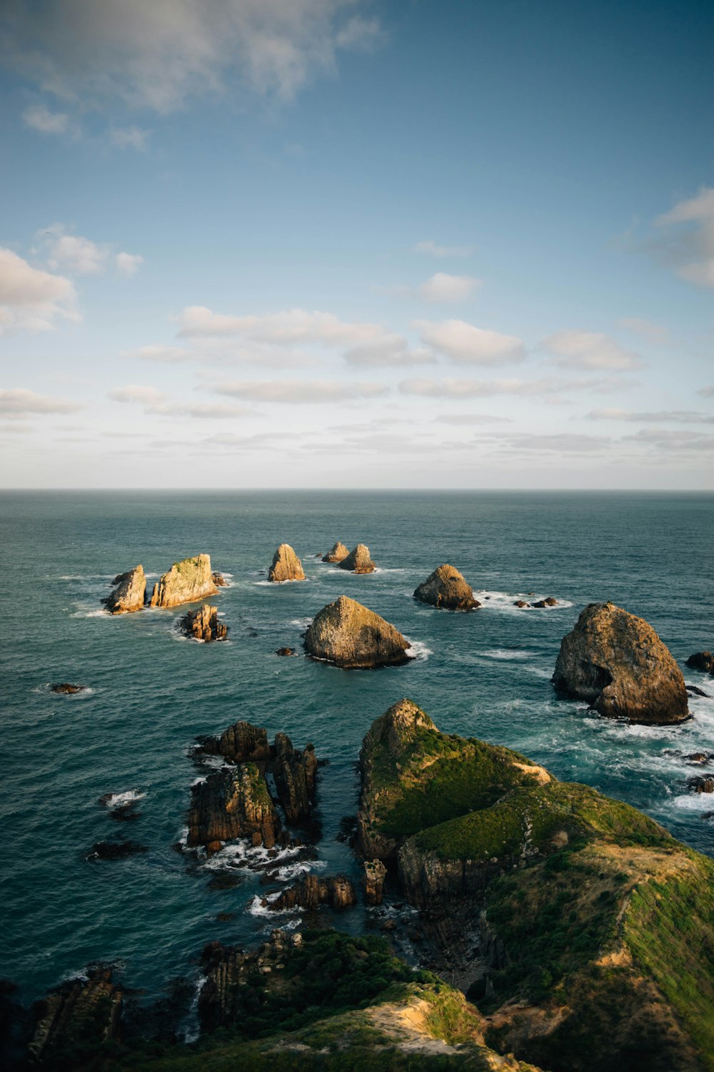 brown rocks on sea under white clouds during daytime