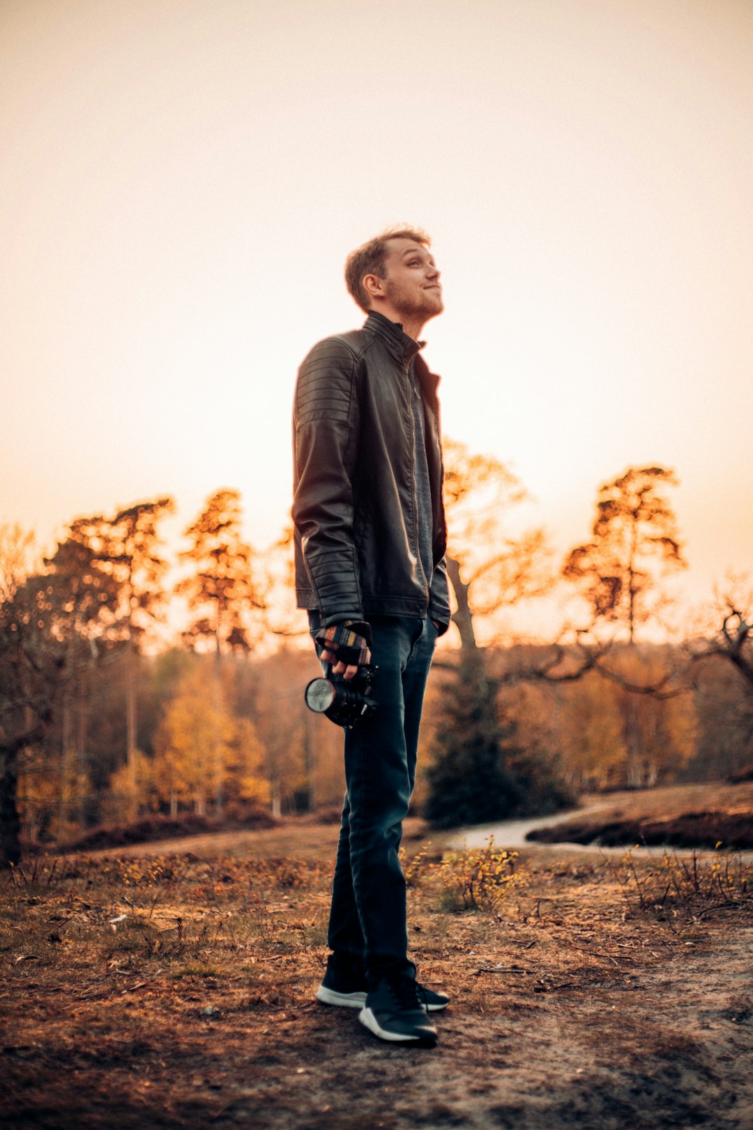 man in brown leather jacket standing on brown field during daytime