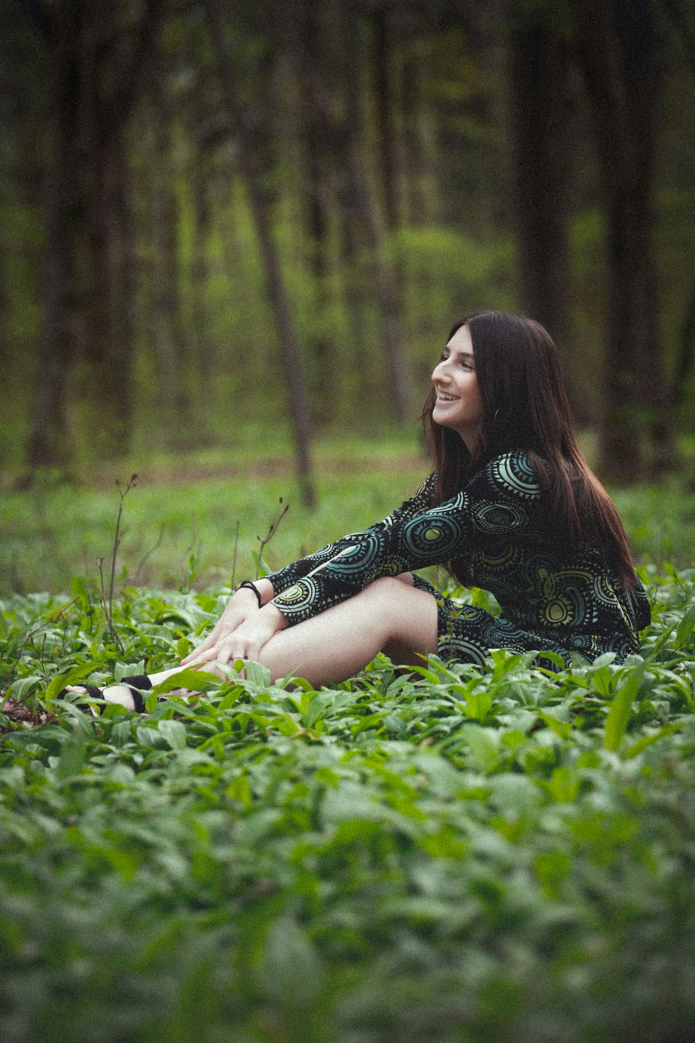 woman in black and white floral dress lying on green grass field