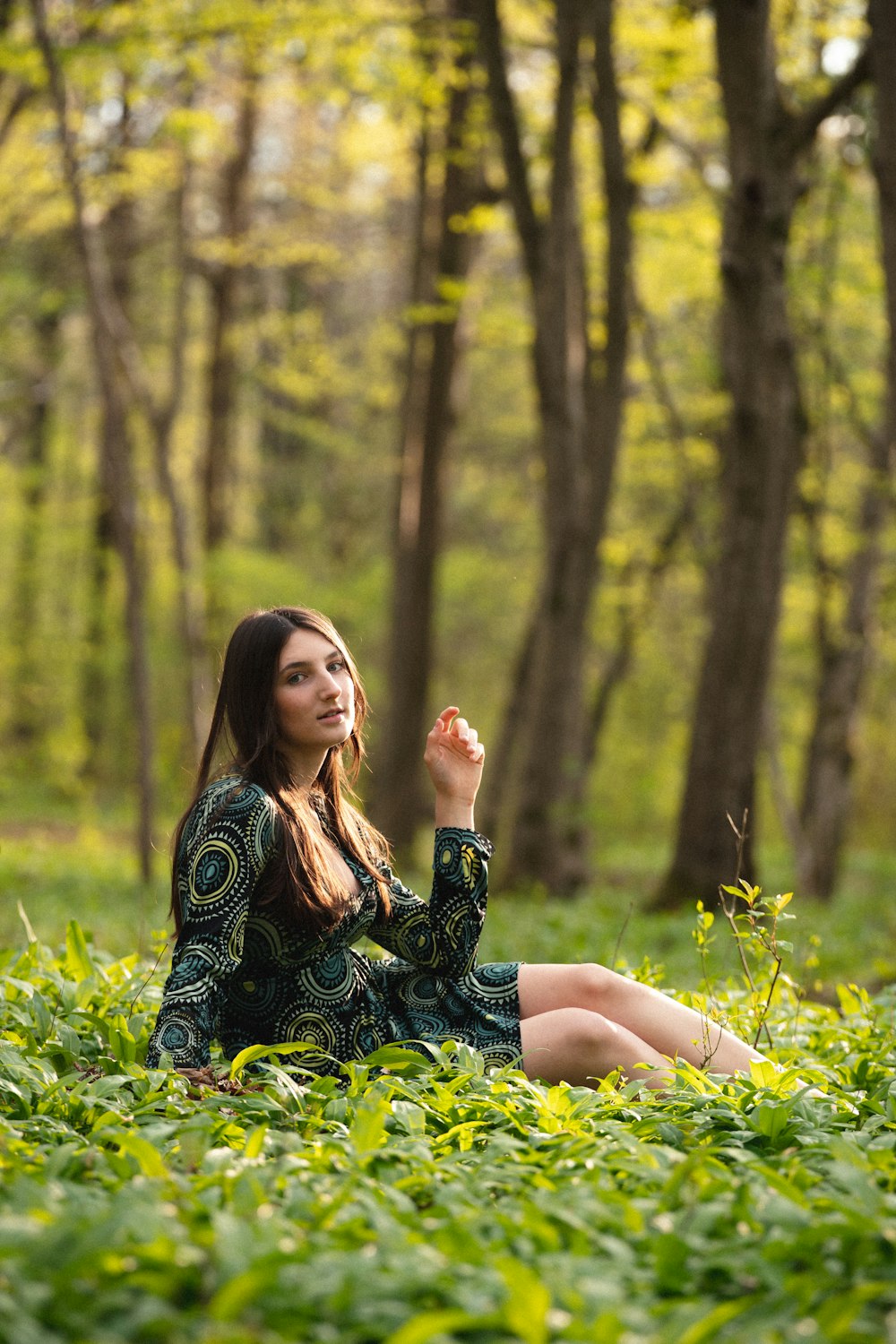 woman in black and white floral dress sitting on green grass during daytime