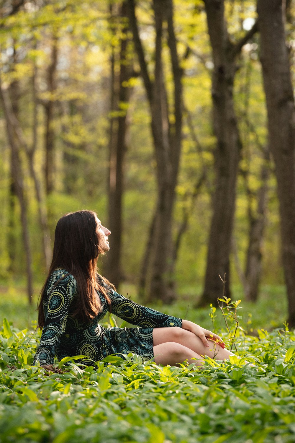 woman in black and white floral long sleeve dress sitting on green grass field during daytime