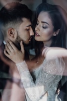 A close-up of a romantic and intimate moment between a couple, with soft lighting and a dreamy atmosphere. The woman is wearing a detailed, lace-patterned garment.