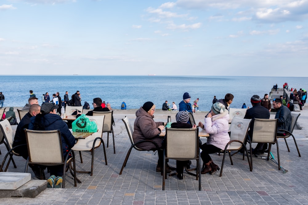 people sitting on chair near sea during daytime