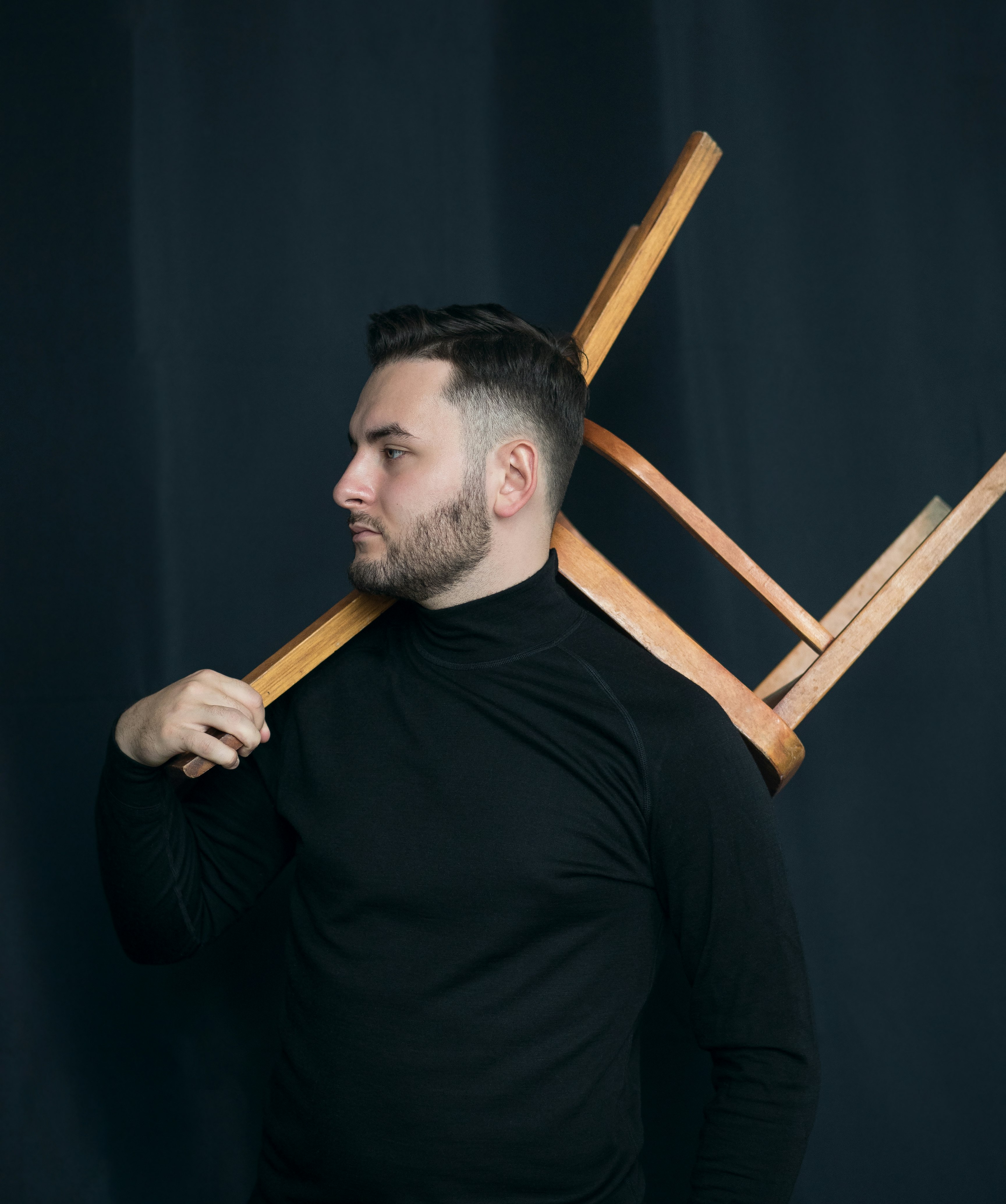 man in black long sleeve shirt holding brown wooden stick