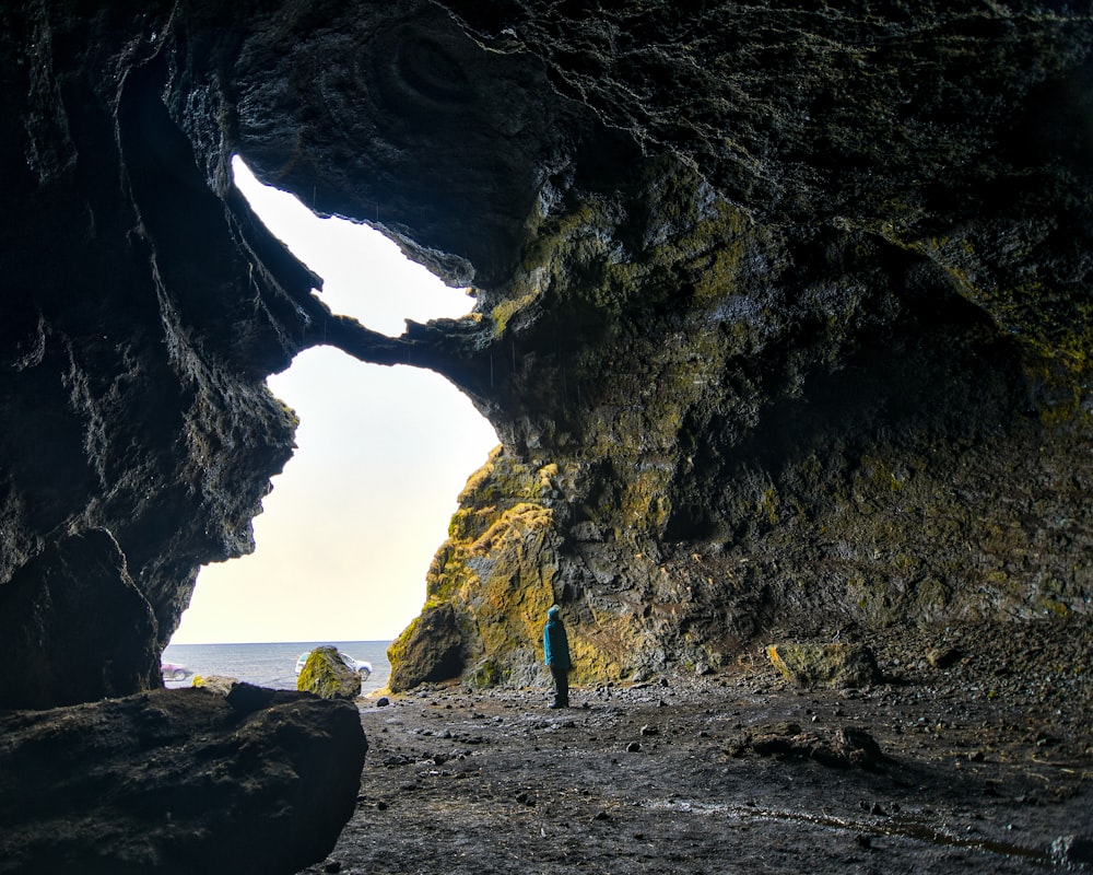 person in blue shirt standing on rock formation during daytime