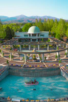 An expansive garden in Riyadh with palm trees, flowering shrubs, and a water fountain centerpiece