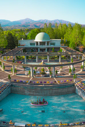 An expansive garden in Riyadh with palm trees, flowering shrubs, and a water fountain centerpiece