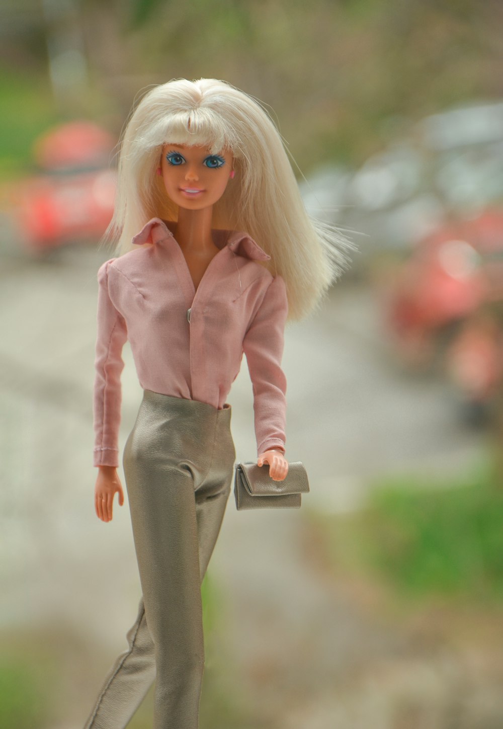 blonde haired girl in pink jacket and gray pants holding brown leather bag